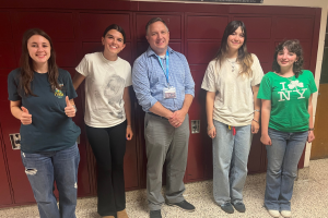  students and teacher posing in high school hallway