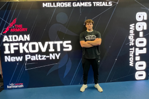   Student poses in front of Millrose Games banner